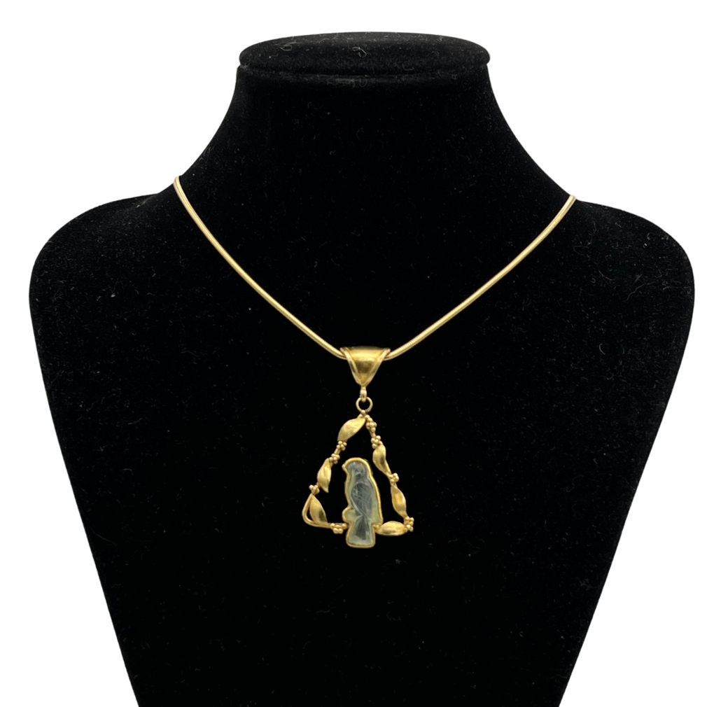 Gold necklace with a bird pendant on a black mannequin bust