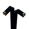 Pair of ladybug earrings on a black stand with a white background